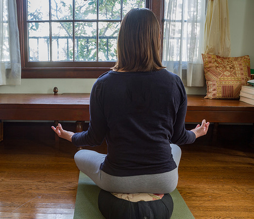 Young woman meditating on cushion