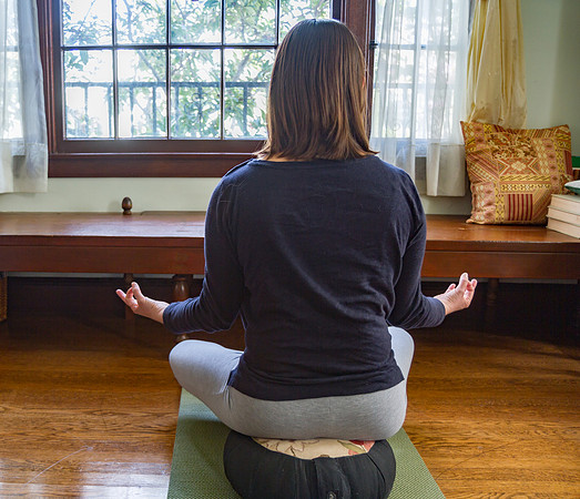 Young woman meditating on cushion