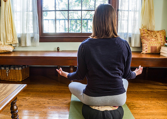 Young woman meditating on cushion